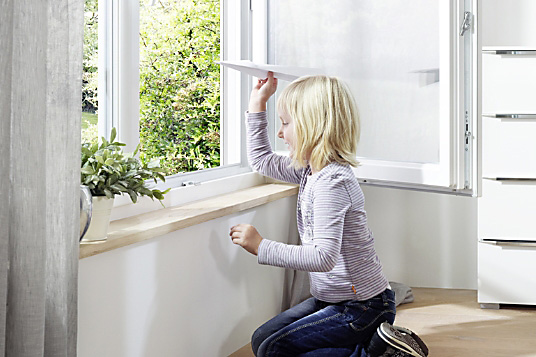 Kind spielt am offenen Brömse Fenster